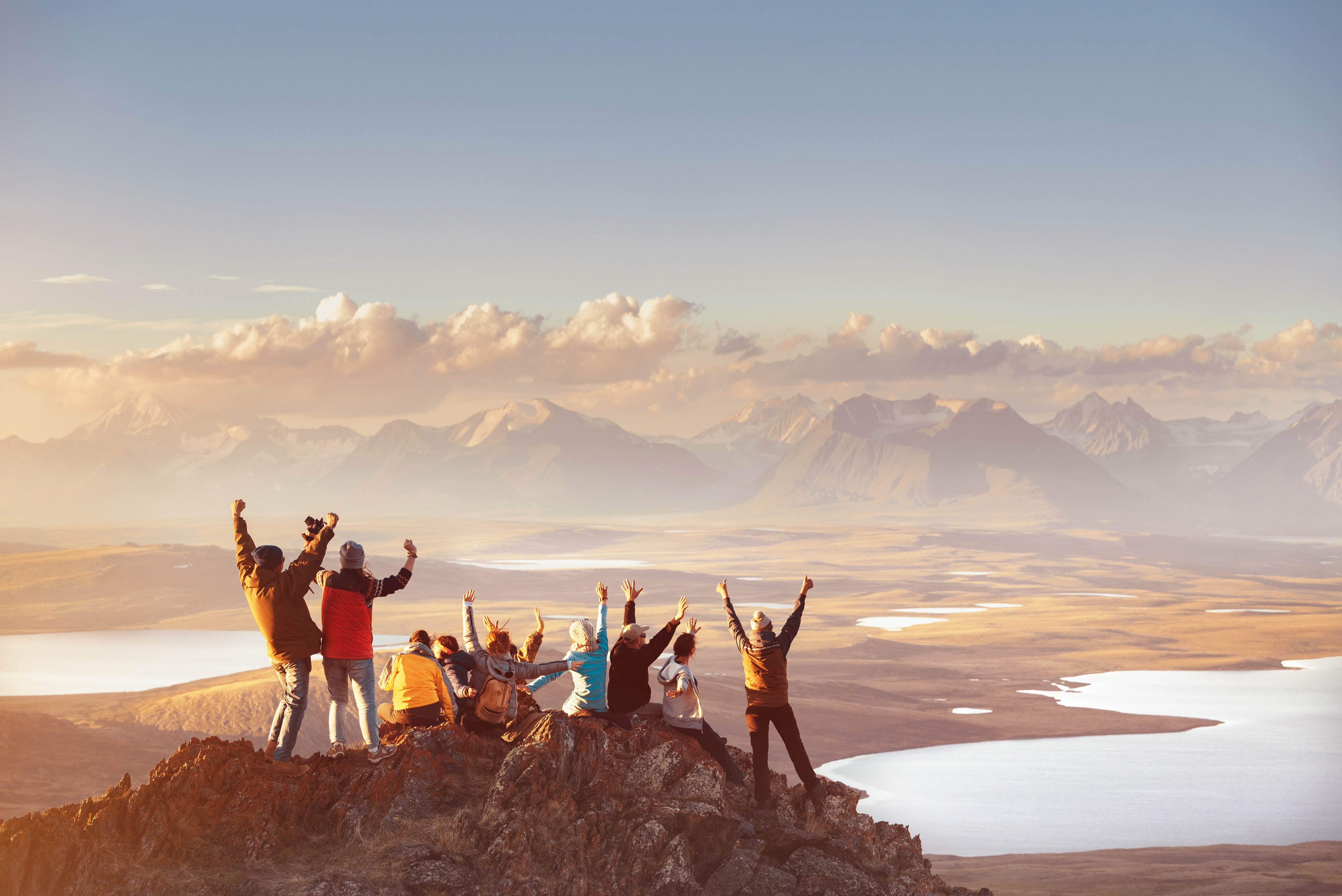 Group of travellers celebrating on a mountain summit overlooking a scenic landscape